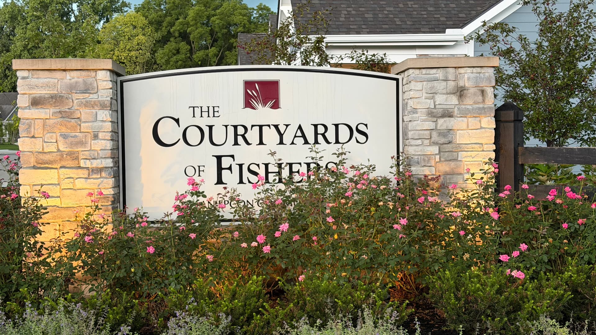 The Courtyards of Fishers stone entrance sign surrounded by roses